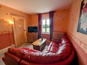 un salon avec un canapé en cuir et une télévision dans l'établissement Appartement rénové au pied des Mille Étangs, 3 chambres - FR-1-583-410, à Mélisey