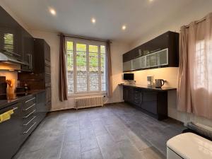 une cuisine avec des armoires noires et une grande fenêtre dans l'établissement Villa des sources en bord de Seine, à La Celle-sur-Seine 28 autres photos