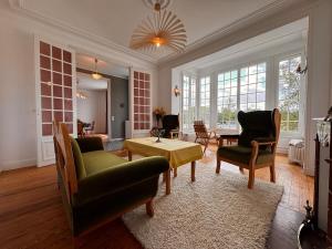 un salon avec des chaises, une table et des fenêtres dans l'établissement Villa des sources en bord de Seine, à La Celle-sur-Seine
