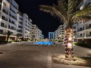 un palmier avec des lumières autour d'une piscine la nuit dans l'établissement sea breeze park residences, à Mekhrably