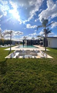 a swimming pool with white chairs and a palm tree at Villa Palms Marrakech in El Aggada +22 photos