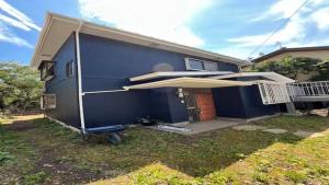 ein blaues Haus mit einem großen Sonnenschirm im Garten in der Unterkunft Boogie Garden - Vacation STAY 06312v in Miyakami