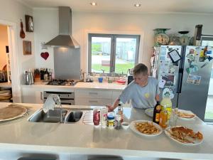 un homme debout à un comptoir de cuisine préparant la nourriture dans l'établissement Ocean Shores Warea,  35 autres photos