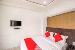 a bedroom with a bed with red pillows and a tv on the wall at Hotel O Eagle Fantasy in Vānivilāsa Puram