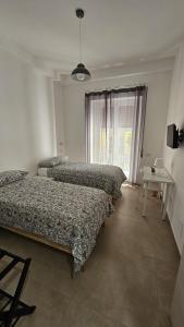 een slaapkamer met 3 bedden, een tafel en een raam bij PETER PAN apartment in Salerno