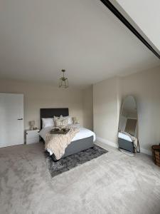 a white bedroom with a bed and a mirror at Stylish 3-Bed Home Close to Newcastle City Centre in Kenton