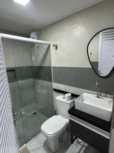 un bagno con un water, un lavandino e uno specchio di Loft lindo e aconchegante 02 a Toritama