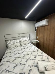 una camera da letto con un letto con un piumone bianco di Loft lindo e aconchegante 02 a Toritama