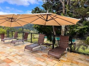 eine Gruppe von Stühlen und ein Sonnenschirm auf einer Terrasse in der Unterkunft Casa maravilhosa com piscina e sauna in Muri
