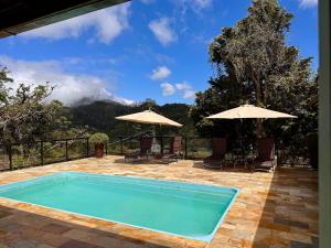 einen Pool mit Stühlen und Sonnenschirmen auf einer Terrasse in der Unterkunft Casa maravilhosa com piscina e sauna in Muri + 77 Fotos