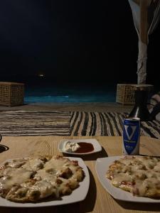 une table avec deux assiettes de pizza et une boisson dans l'établissement Sea View Camp, à Wāsiţ