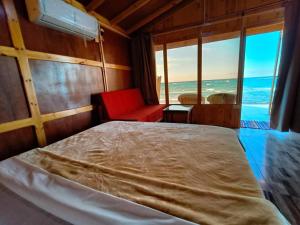une chambre avec un lit et une chaise rouge et l'océan dans l'établissement Sea View Camp, à Wāsiţ 30 autres photos