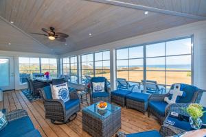 a screened in porch with blue furniture and a ceiling fan at Blue Ocean Cove Beach House in Saint Peters