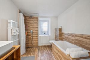 une salle de bain avec une baignoire blanche et une douche dans l'établissement Lodge of Sardona, à Schwanden