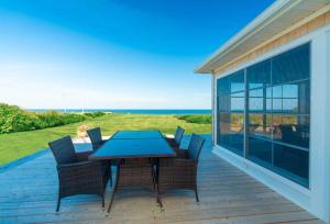 een terras met een tafel en stoelen op een dek bij Blue Ocean Cove Beach House in Saint Peters
