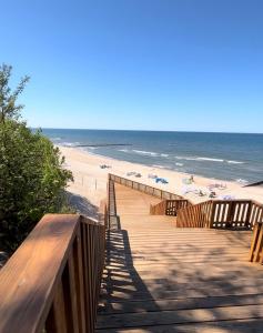 une promenade en bois menant à une plage avec des parasols dans l'établissement Shells & Pearls Rewal - Wakacyjny apartament blisko morza, à Rewal