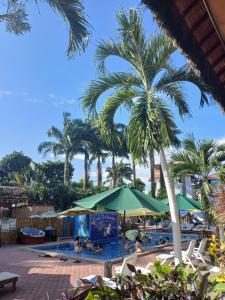 a resort with a pool with palm trees and umbrellas at Casa Del Merman at GayMontanita House in Montañita