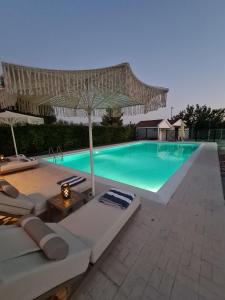 a swimming pool with an umbrella and some chairs and an umbrella at Villa ChrysPa Attica in Dhílesi
