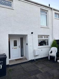 a white house with a white door and a white chair at OakHouse- Entire 3 Bedroom Terrace House with Free Parking in Cumbernauld