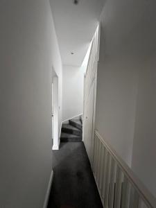 a hallway with white walls and a stair case at Belin Stay in Hackbridge