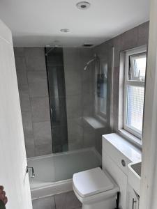 a bathroom with a shower and a toilet and a sink at Belin Stay in Hackbridge