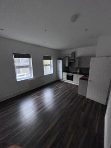 an empty living room with wooden floors and windows at Belin Stay in Hackbridge