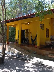 ein gelbes Haus mit einer Hängematte davor in der Unterkunft Recanto Gira Cerrado in Cavalcante