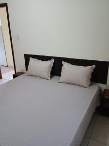 a bed with two pillows on top of it at Ap 2 quartos aconchegante com ar-condicionado in Viçosa