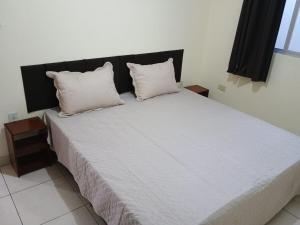 a bedroom with a large bed with two pillows at Ap 2 quartos aconchegante com ar-condicionado in Viçosa +4 photos
