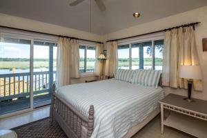 Schlafzimmer mit einem Bett und einem Balkon mit Fenstern in der Unterkunft Shrimpers Cove in Edisto Island