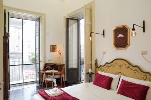 1 dormitorio con cama con almohadas rojas y escritorio en SantuzzaMia, en Catania