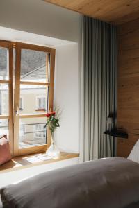 a bedroom with a bed and a window with a vase of flowers at Mesnerhaus & Gourmetrestaurant Mesnerhaus mit 4 Hauben in Mauterndorf