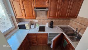 a kitchen with wooden cabinets and a sink and a microwave at Jokai sor II Apartman in Hajdúszoboszló