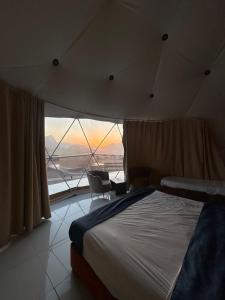 a bedroom with a large bed and a large window at Bubbles Desert Camp Jeep Tours in Disah