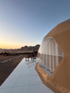 a tent on the beach with benches in the distance at Bubbles Desert Camp Jeep Tours in Wadi Rum +84 photos