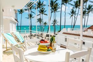 蓬塔卡纳OLAS TROPICAL at playa LOS CORALES - villas, suites and studios的俯瞰大海的阳台的水果桌