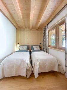 two beds in a bedroom with a wooden ceiling at Chalet Sole delle Dolomiti in Varda