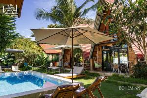 einen Pool mit Sonnenschirm und Stühlen neben einem Haus in der Unterkunft Cabañas Alpinas en Oxapampa in Oxapampa