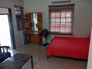 a bedroom with a red bed and a desk and window at Diamond Breeze - Fully furnished apartment in Port-of-Spain
