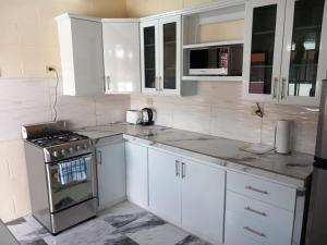 a white kitchen with a stove and white cabinets at Diamond Breeze - Fully furnished apartment in Port-of-Spain