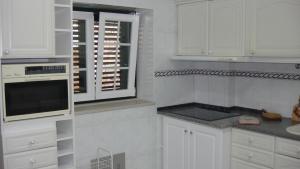 a white kitchen with white cabinets and a window at Casa de Férias Azeitão in Azeitao