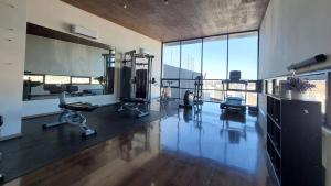 a gym with cardio equipment in a room with large windows at Amar Apartment - 24 hour security, Comfort in Tijuana