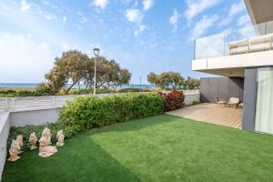 une maison avec une pelouse devant un immeuble dans l'établissement מיקונוס על הים נהריה, à Nahariya