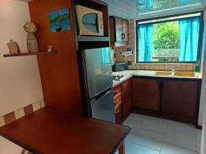 une cuisine avec un réfrigérateur et une table à l'intérieur dans l'établissement La PERLE de MOOREA Fare HONU Bord de Lagon, à Orufara