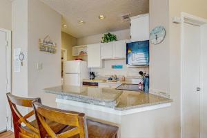 a kitchen with white cabinets and a counter with two chairs at Beach Club 280 in Padre Island