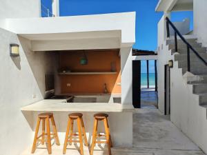 ChuburnáOn Beach Seaside Sunset Haven 1 Nature & Chill的厨房配有2把凳子,旁边是柜台