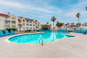 パドレ・アイランドにあるBeach Club - Resting Beach Faceの青い椅子とヤシの木があるリゾートのスイミングプール