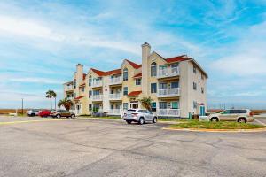 パドレ・アイランドにあるBeach Club - Resting Beach Faceの駐車場に車が駐車されている大きなアパート