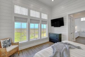 Un dormitorio con una cama y un televisor y ventanas. en Seaside Paradise, en Mustang Beach