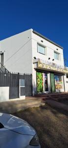 ein weißes Gebäude mit einem Zaun davor in der Unterkunft Departamento familiar in Caleta Olivia